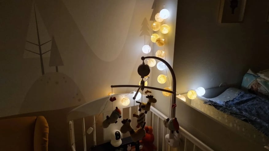 Dětský pokoj s postýlkou a světelným řetězem.